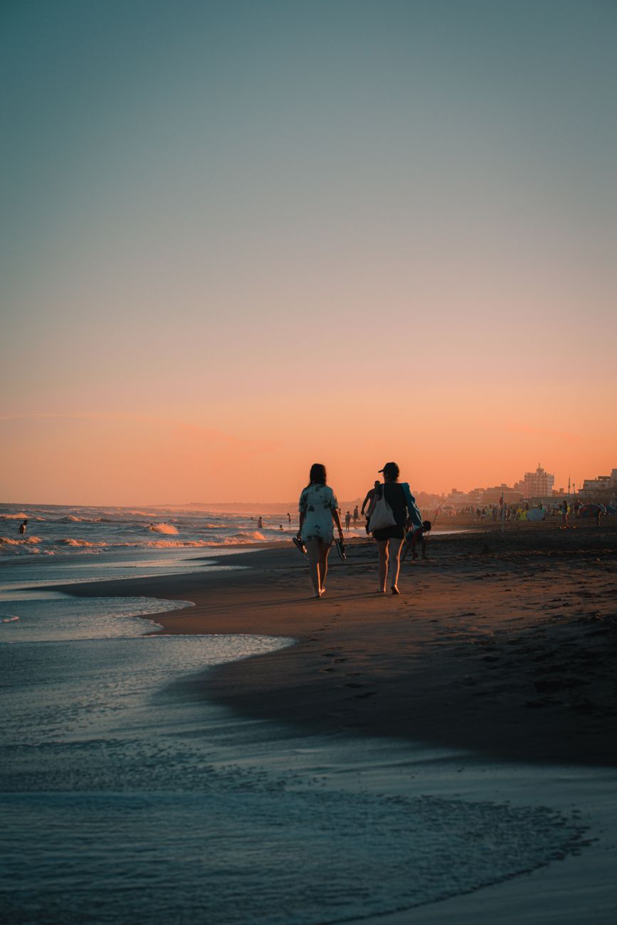 Two people walking along a beach at sunset, representing the long runway before an advisor retires