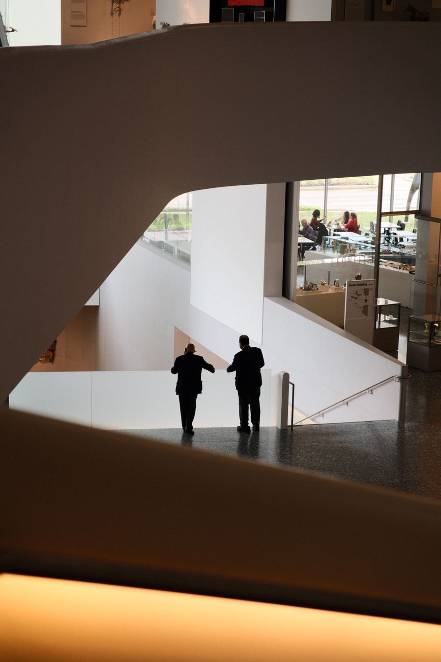 Two advisors in suits walking through a modern office building atrium