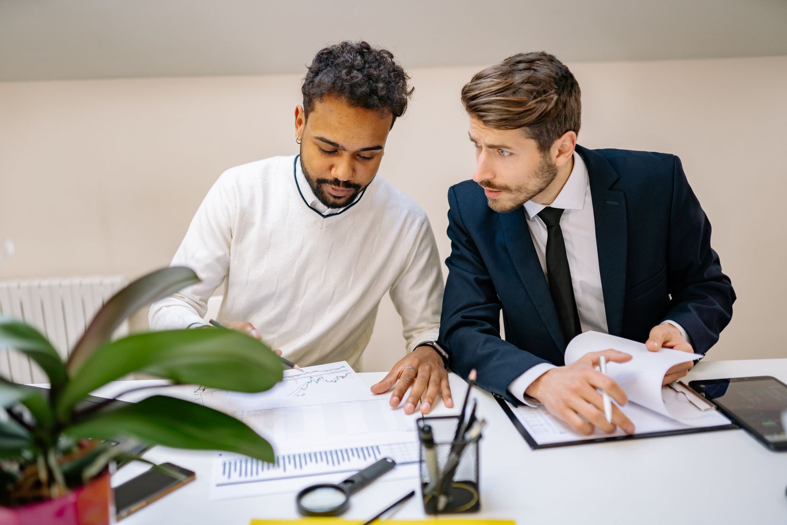 A financial advisor and a support staff member reviewing paperwork together at a desk.