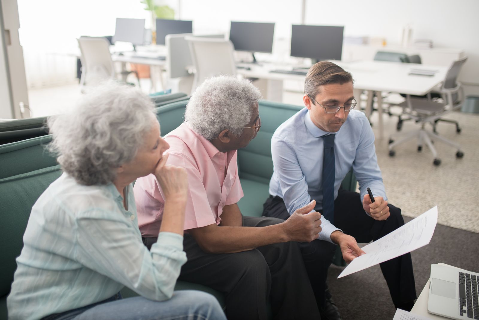 A financial advisor showing a document to an older married couple during a claiming conversation.