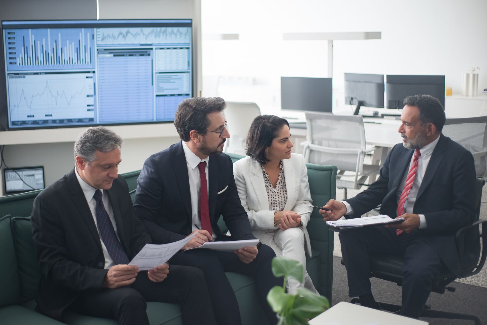 A small team of advisors reviewing multiple trading and account screens together in an office.