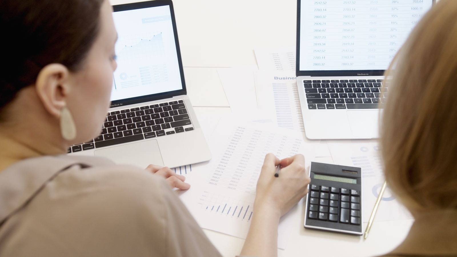 A younger advisor and a client reviewing figures together with a calculator.